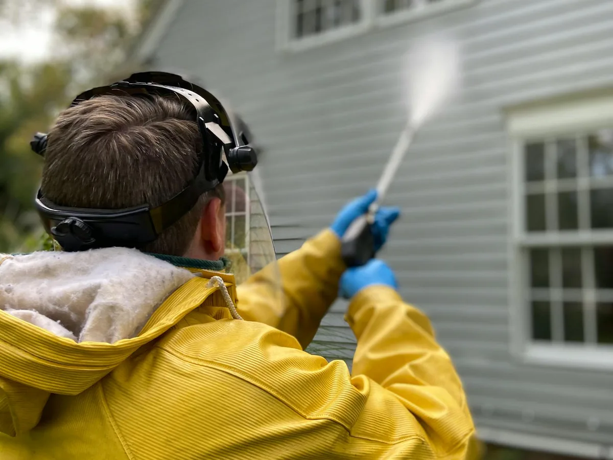 Crew member pressure washing siding on a home